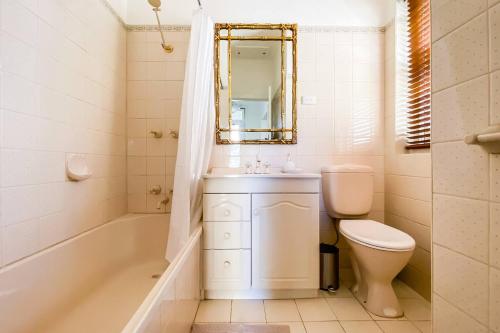 a bathroom with a tub and a toilet and a sink at 'The Gables' Stylish Victorian Beachfront Abode in Melbourne