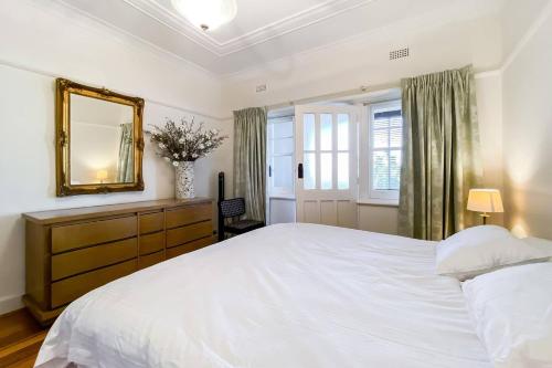 a bedroom with a large white bed and a mirror at 'The Gables' Stylish Victorian Beachfront Abode in Melbourne