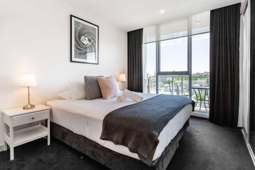 a bedroom with a large bed and a large window at City View Chic in South Yarra with Parking in Melbourne