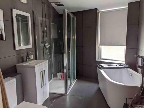 y baño con ducha, bañera y lavamanos. en Central Newquay Terrace House en Newquay