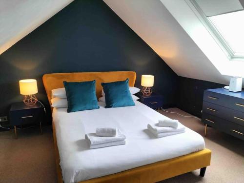 a bedroom with a large white bed with blue pillows at Central Newquay Terrace House in Newquay