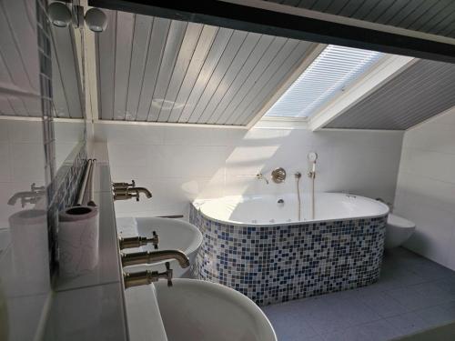 a bathroom with a tub and two sinks and a skylight at Holiday home in rural area with private garden in Leende