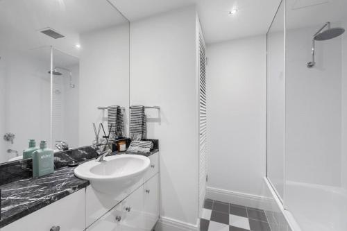 a white bathroom with a sink and a shower at 'The Skyforest' An Elegant Urban Oasis in Melbourne