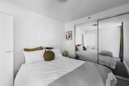 a bedroom with a large white bed and a mirror at 'The Skyforest' An Elegant Urban Oasis in Melbourne