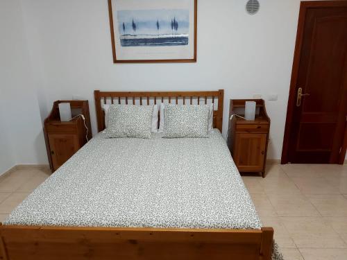 a bedroom with a wooden bed with two night stands at NIVARIA SUITE in Vecindario