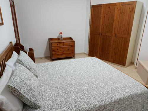 a bedroom with a large bed and a wooden dresser at NIVARIA SUITE in Vecindario