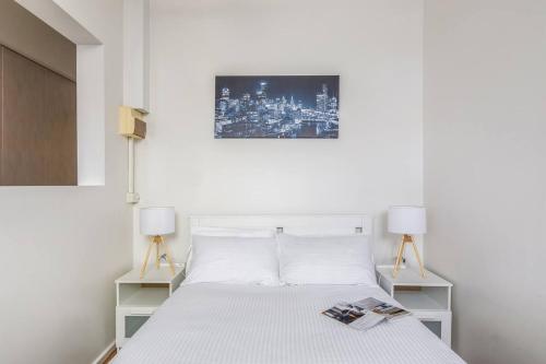 a white bedroom with a white bed with two lamps at Studio Elizabeth - A Cosy and Central CBD Hidden Gem in Melbourne