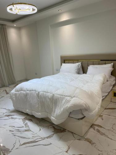 1 dormitorio con 1 cama blanca grande y suelo de mármol en Helio, en El Cairo