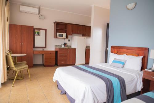 a bedroom with a bed and a desk and a kitchen at Hotel y Restaurante El Guarco in Cartago