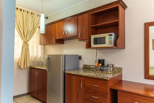 a kitchen with wooden cabinets and a stainless steel refrigerator at Hotel y Restaurante El Guarco in Cartago