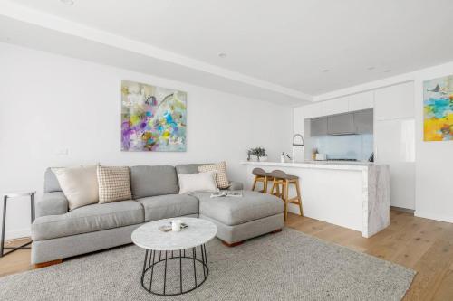 a white living room with a couch and a table at The Nest on Nott - Pure Port Melbourne Bliss in Melbourne