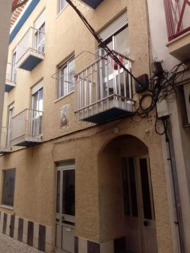 a building with a balcony on the side of it at Apartamentos das Avós-Flor in Nazaré