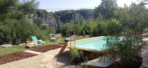 a swimming pool in a garden with a mountain in the background at A la Source in Saint-Cirq-Lapopie