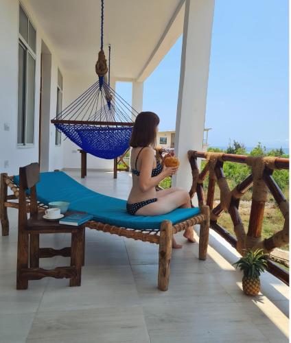 a woman sitting on a hammock on a porch at Five Seasons Zanzibar Ocean apartments in Muyuni