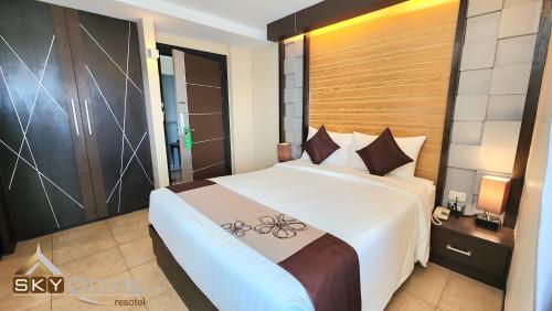 a bedroom with a large white bed with a wooden headboard at Sky dome resotel - โรงแรมสกายโดม รีโซเทล in Bangkok