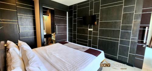 a bedroom with a bed and a tiled wall at Sky dome resotel - โรงแรมสกายโดม รีโซเทล in Bangkok