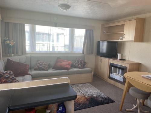 a living room with a couch and a television at 2 Bedroom Caravan - Ash 51, Trecco Bay in Newton