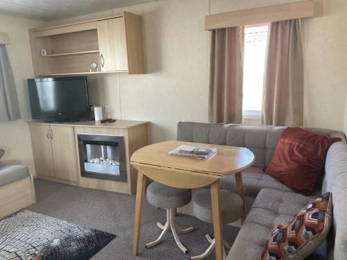uma sala de estar com um sofá e uma mesa em 2 Bedroom Caravan - Ash 51, Trecco Bay em Newton