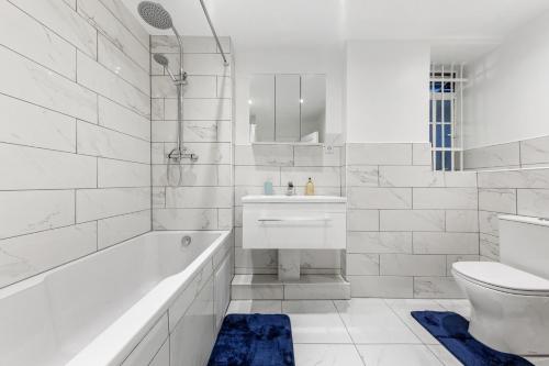 a white bathroom with a tub and a sink and a toilet at Modern Flat in London in London