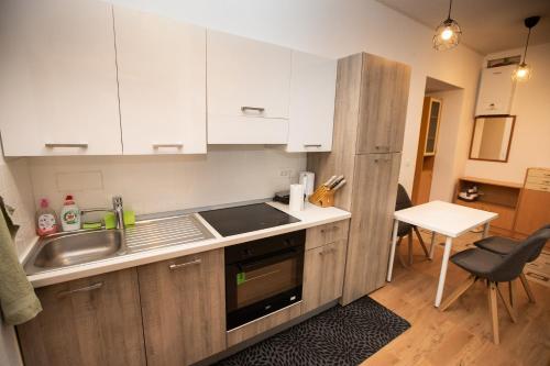 a kitchen with white cabinets and a sink and a table at Newly adapted 3-room apartment in Postojna