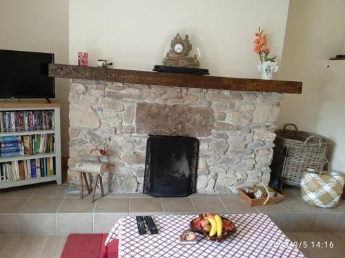 a living room with a stone fireplace with a table at Nire Valley Cottage 