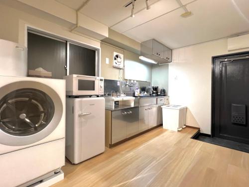 a kitchen with a washing machine and a microwave at 山手線池袋駅 徒歩6分 東池袋駅徒歩3分 2~5人 エレベーター WIFI 新宿/渋谷/銀座/築地/浅草/原宿近い！ in Tokyo