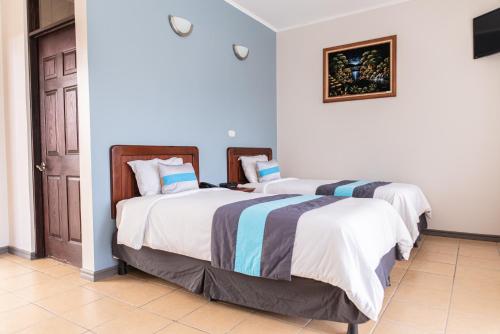 two beds in a room with a door at Hotel y Restaurante El Guarco in Cartago