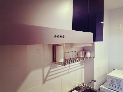 eine Küche mit einem weißen Schrank und einem Regal in der Unterkunft Brand New Shinjuku Station 5 Mins - Apartment D in Tokio
