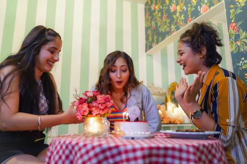 three women standing around a table with a cake at Stay Banaras - A Boutique Hotel in Varanasi