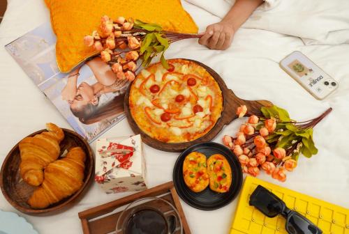 a person laying on a bed with a pizza and other foods at Stay Banaras - A Boutique Hotel in Varanasi