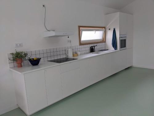 a white kitchen with a sink and a window at Modern and spacious Cork House with private valley view in Caldas da Rainha