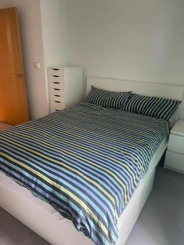 a bed with a striped comforter in a bedroom at Luxurious NEW 2 Bed apartment in London