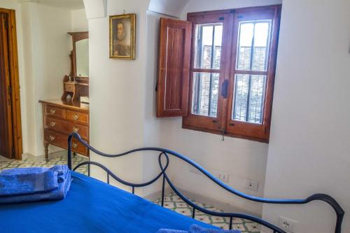a bedroom with a blue bed and a dresser and window at Dammuso i Pini di Kaddiuggia (CIR19081014C224053) & Dammuso di Mena (CIR 19081014C224052 in Pantelleria