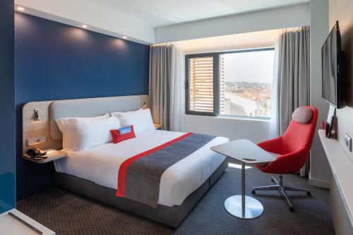 a hotel room with a bed and a red chair at Holiday Inn Express Porto City Centre, an IHG Hotel in Porto