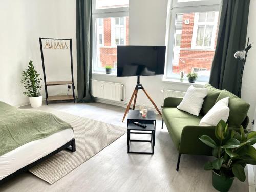 a living room with a green couch and a tv at ENDLESS: Studio mit Netflix + Workstation im Zentrum in Schwerin