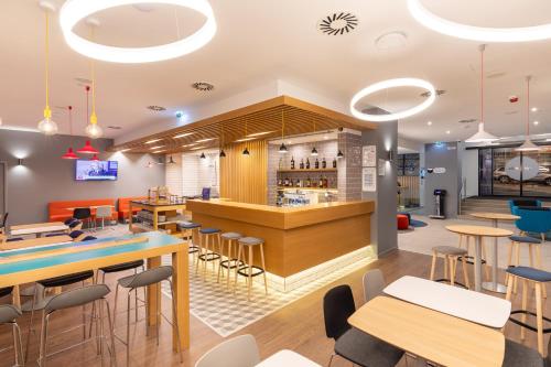 a restaurant with a bar and tables and chairs at Holiday Inn Express Porto City Centre, an IHG Hotel in Porto