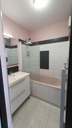 La salle de bains est pourvue d'une baignoire rose, d'un lavabo et d'une baignoire. dans l'établissement Grand Bleu-Studio vue sur mer - piscine, à Les Sables-dʼOlonne