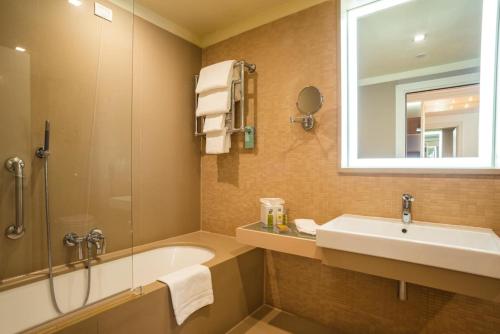 bagno con lavandino, vasca e specchio di Hilton Garden Inn Florence Novoli a Firenze