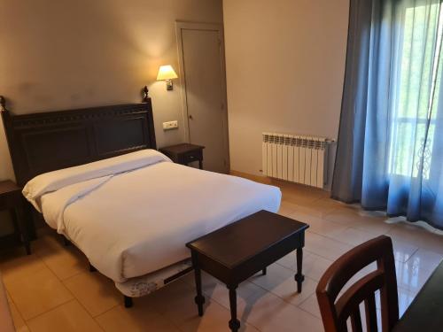 a bedroom with a white bed and a table and a window at Hotel Restaurante Ribera del Chicu in Arriondas