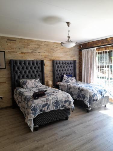 a bedroom with two beds and a chair and a window at Chappel Hide Out in Germiston