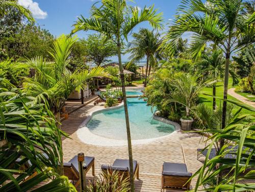 a swimming pool in a resort with palm trees at Pousada Mi Secreto in São Miguel do Gostoso