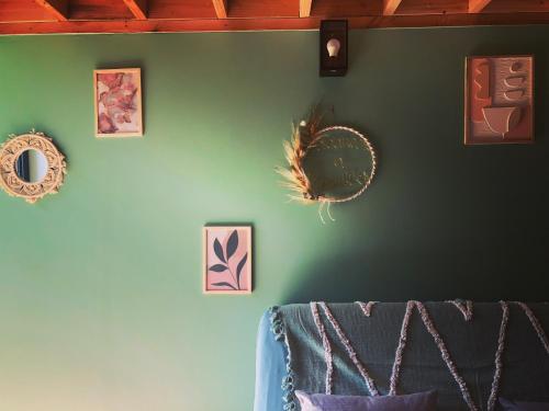 a green wall with pictures and mirrors on it at Maisonnette jardin jacuzzi au cœur de Chambles in Chambles