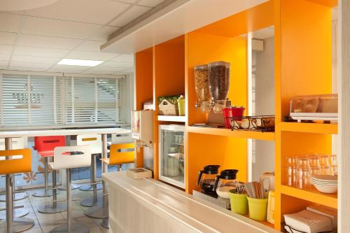 une cuisine avec des armoires orange et jaune dans l'établissement Première Classe Clermont-Ferrand Aubière, à Aubière