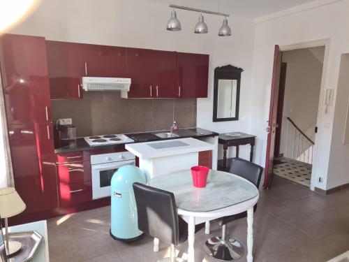 une cuisine avec des armoires rouges et une table avec une tasse rouge dessus dans l'établissement La MASCOTTE 3, à Vallauris