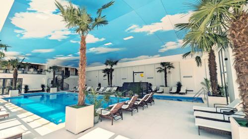 a resort pool with chairs and a palm tree at Complex Parc Pini Moinesti in Moineşti