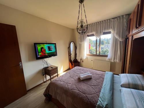- une chambre avec un lit et une télévision murale dans l'établissement Apartamento Edelweiss 403, à Gramado
