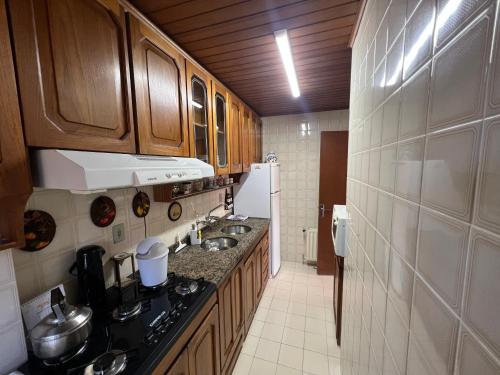 - une cuisine avec des placards en bois et un comptoir dans l'établissement Apartamento Edelweiss 403, à Gramado