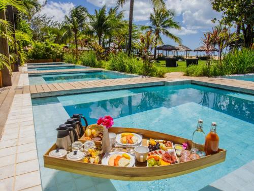 a tray of food in a boat in front of a swimming pool at Pousada Mi Secreto in São Miguel do Gostoso
