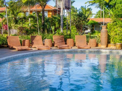 a row of wicker chairs next to a swimming pool at Pousada Mi Secreto in São Miguel do Gostoso