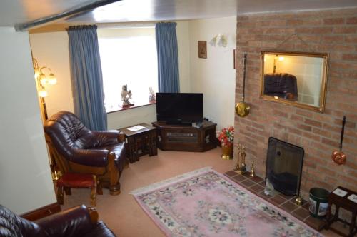 uma sala de estar com um sofá e uma televisão em Oak house hotel em Wellingborough